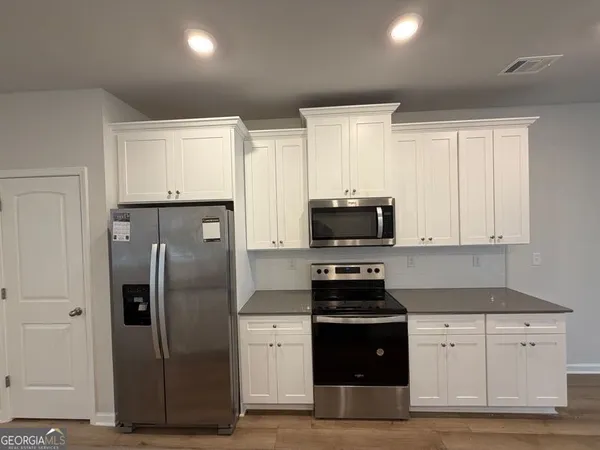 a kitchen with refrigerator cabinets and wooden floor