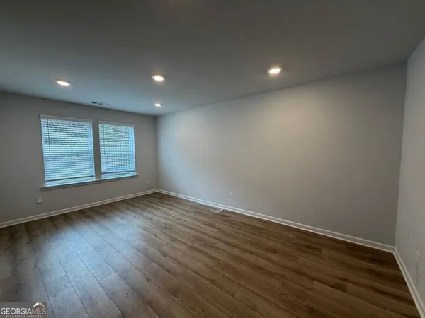 an empty room with wooden floor and windows