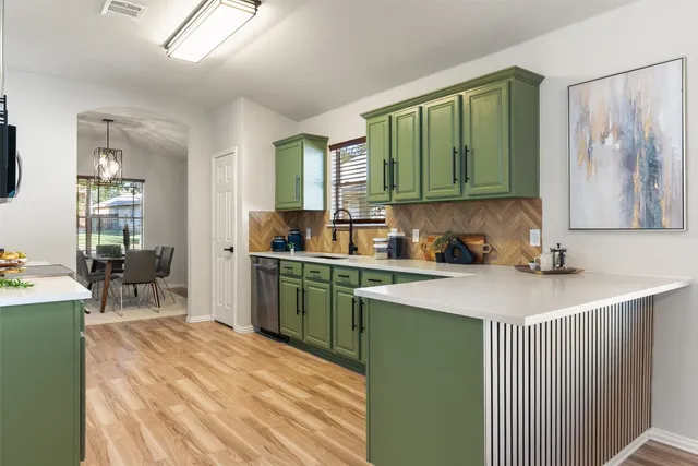 a kitchen with stainless steel appliances granite countertop a stove top oven a sink dishwasher and cabinets with wooden floor