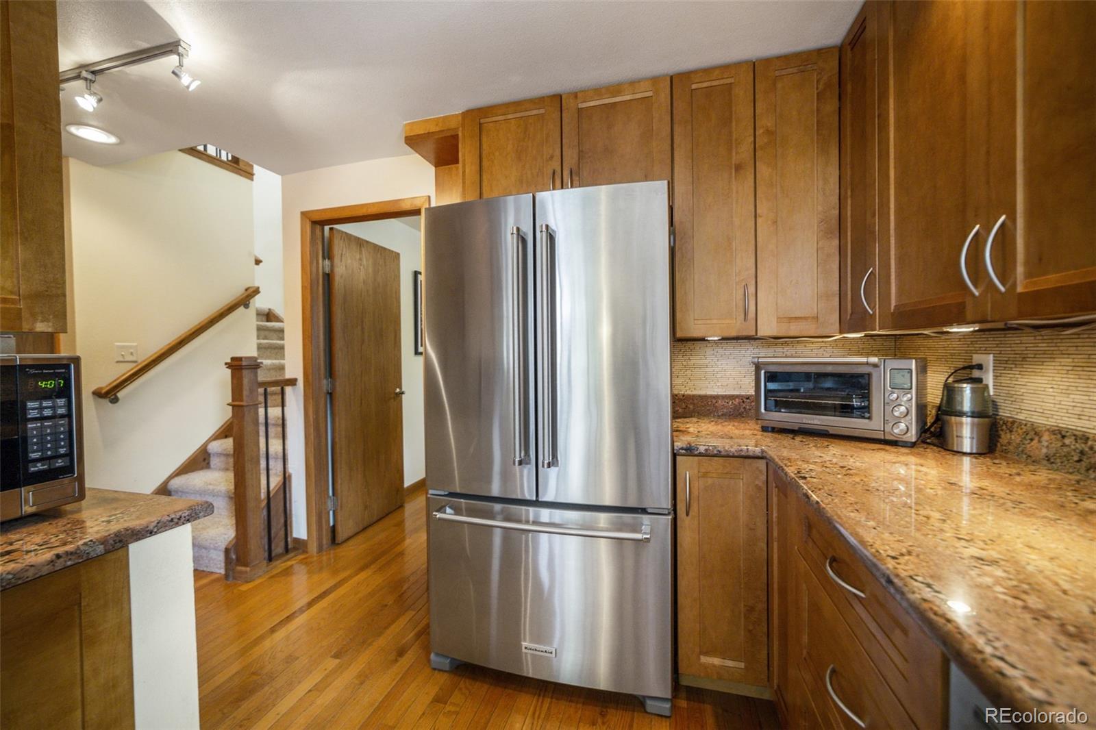 4780 McKinley Drive Boulder, CO 80303 - Photo 8 of 37 a kitchen with stainless steel appliances granite countertop a refrigerator a stove and a sink with wooden floor