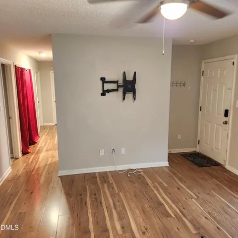 a view of a room with wooden floor and a ceiling fan