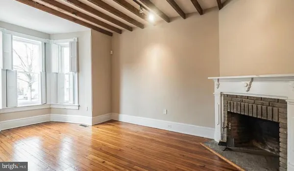 an empty room with wooden floor fireplace and windows