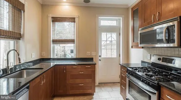 a kitchen with granite countertop cabinets stainless steel appliances a sink and a window