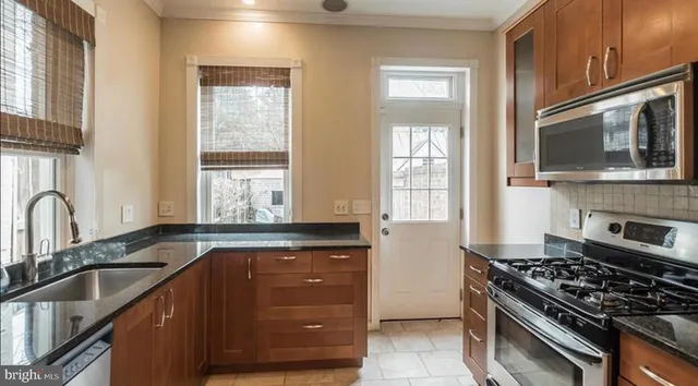 a kitchen with granite countertop cabinets stainless steel appliances a sink and a window