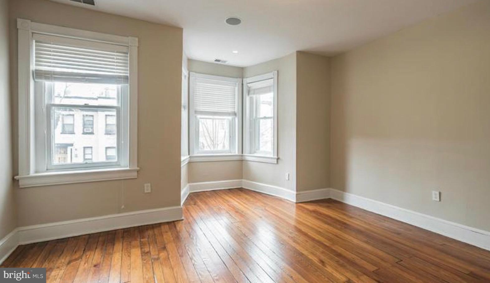 1319 35th Street Northwest Washington, DC 20007 - Photo 14 of 20 an empty room with wooden floor and windows