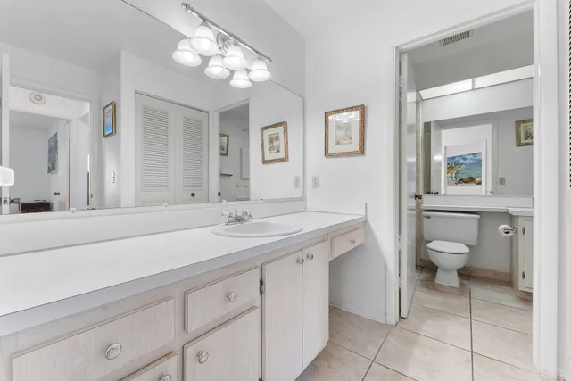 a spacious bathroom with a granite countertop sink a toilet and a mirror