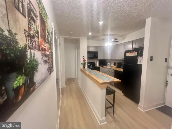 a large kitchen with stainless steel appliances kitchen island a large counter top and living room view