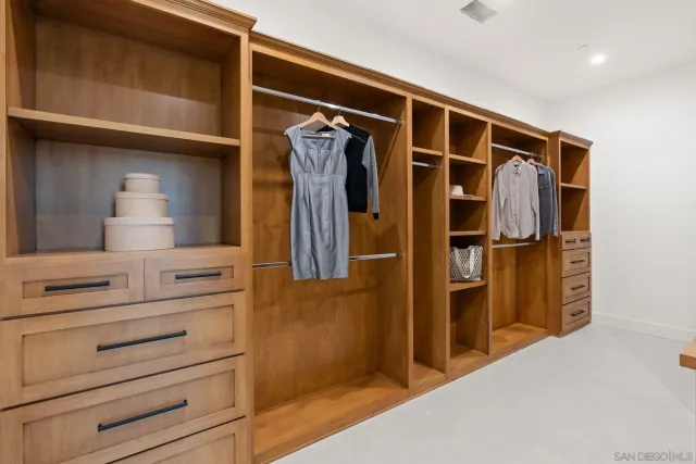 a view of walk in closet with clothes and shoes