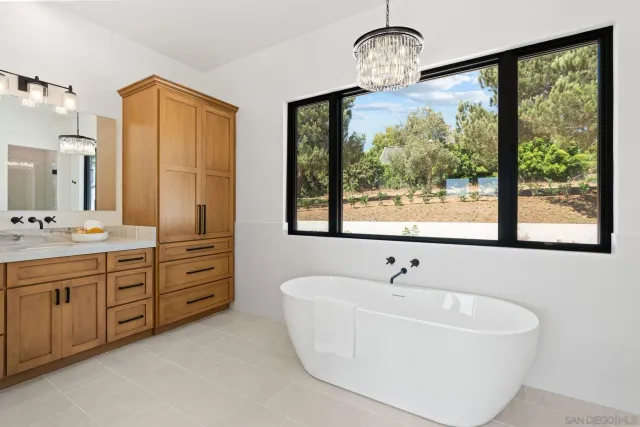 a spacious bathroom with a double vanity sink a two mirror a window and a shower
