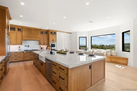 a large white kitchen with a large window and stainless steel appliances