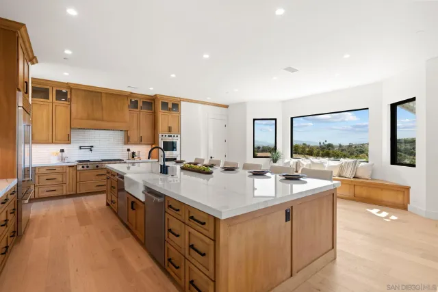 a large white kitchen with a large window and stainless steel appliances