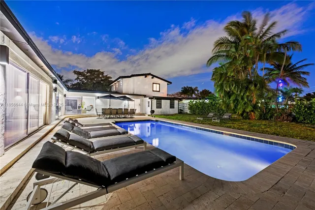 a house view with swimming pool and chairs