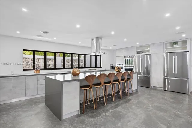 a large dining hall with stainless steel appliances granite countertop a living room a couches with kitchen island a stove and a sink