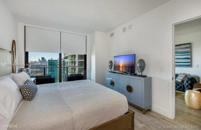 a bedroom with a bed a flat screen tv and balcony view
