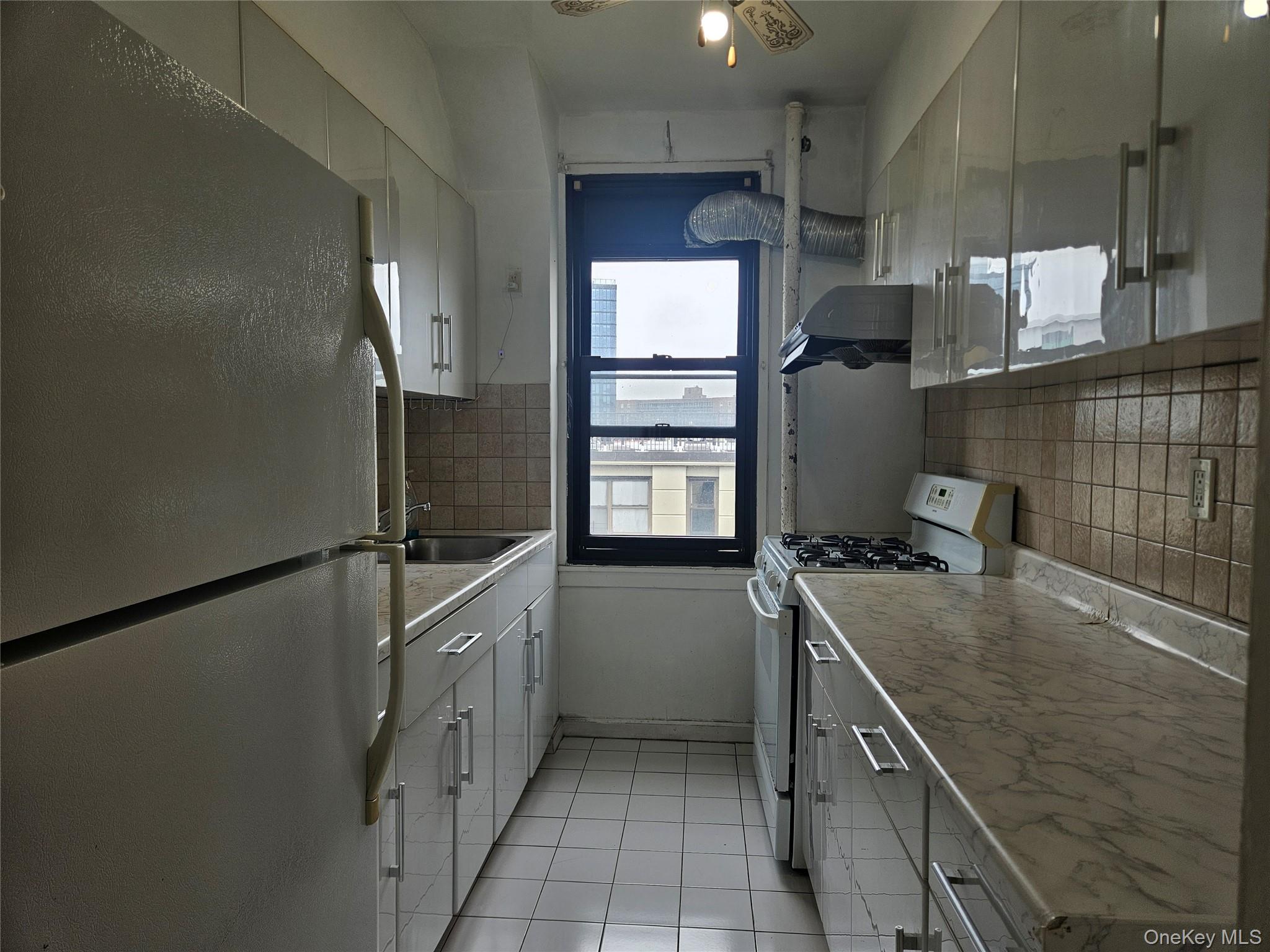 98-25 64th Road, Unit 8F Queens, NY 11374 - Photo 4 of 8 a kitchen with a sink stove and refrigerator
