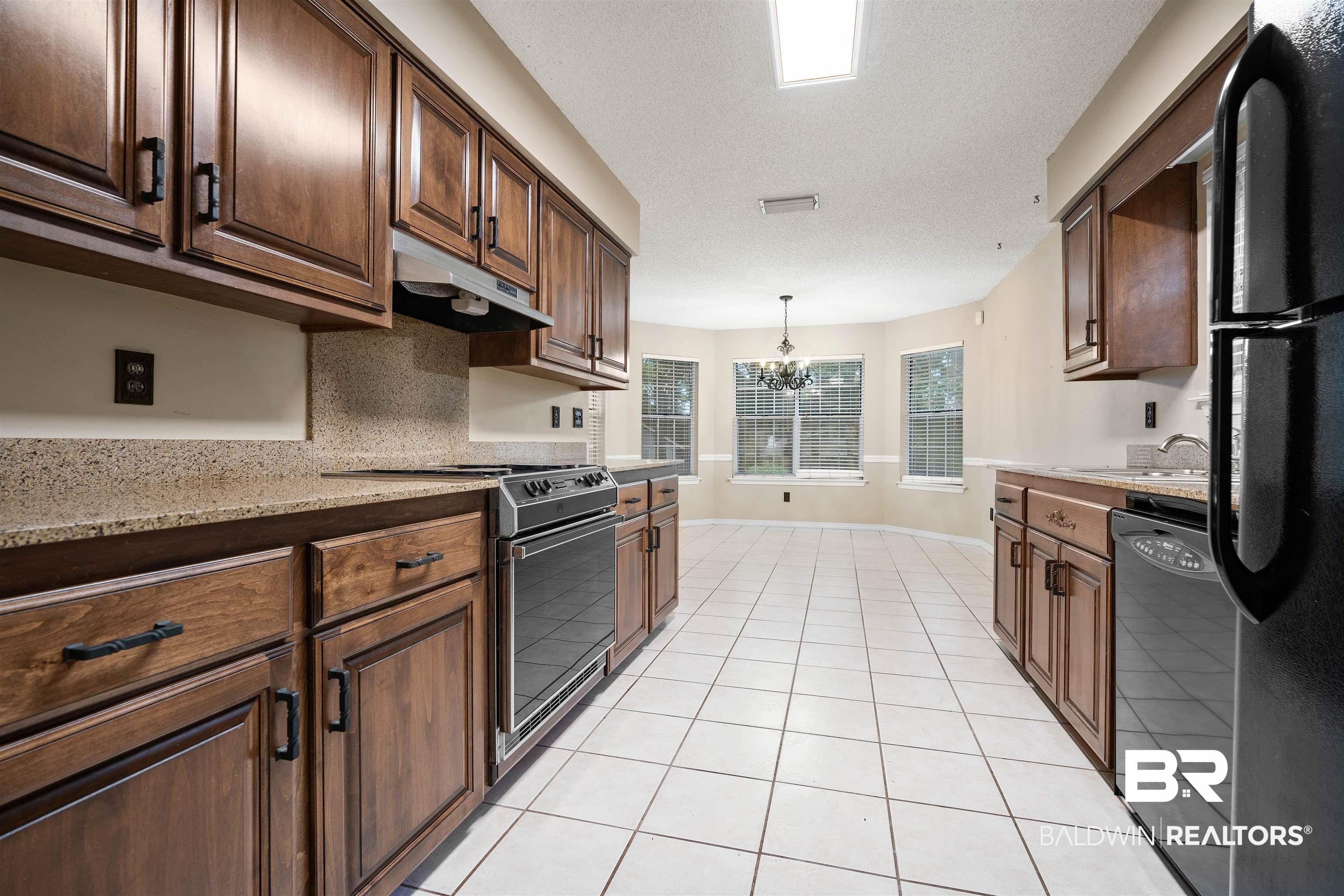 7100 Huntington Court South Mobile, AL 36619 - Photo 14 of 30 Kitchen with black appliances, light stone countertops, light tile patterned floors, hanging light fixtures, and a chandelier