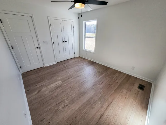 a view of an empty room with a window and wooden floor