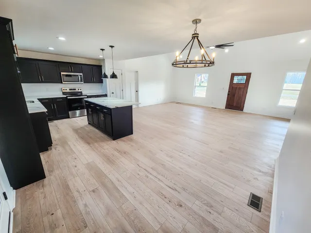 a large kitchen with stainless steel appliances a large counter top a stove and a refrigerator