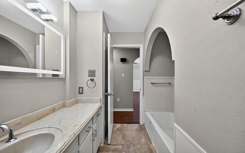 220 Short Street Burleson, TX 76028 - Photo 23 of 36 a bathroom with a granite countertop sink a mirror and a bathtub