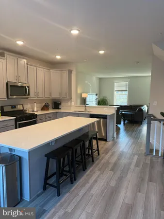 a kitchen with stainless steel appliances granite countertop a table chairs sink refrigerator and cabinets