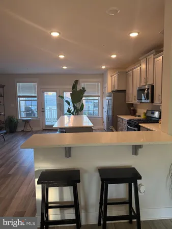a kitchen with stainless steel appliances a dining table chairs microwave and sink