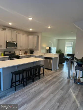 a kitchen with stainless steel appliances granite countertop a table chairs sink refrigerator and cabinets