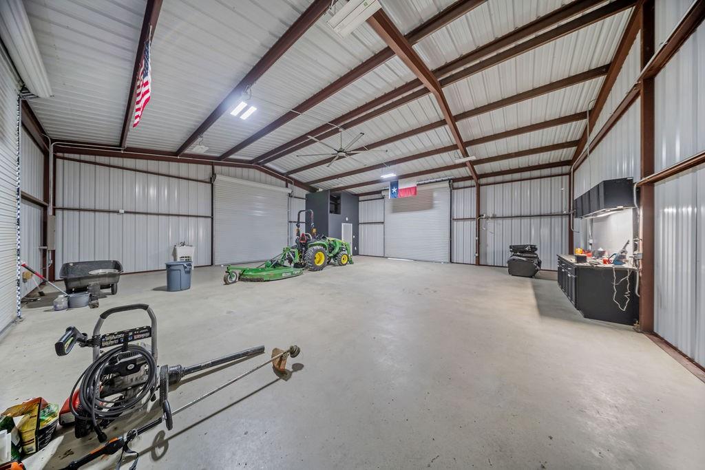 1161 Alsdorf Road Ennis, TX 75119 - Photo 20 of 28 Expansive metal building featuring a concrete floor, exposed steel beam construction, corrugated metal walls, and multiple overhead doors