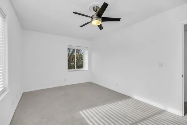 a view of a big room with a ceiling fan and windows