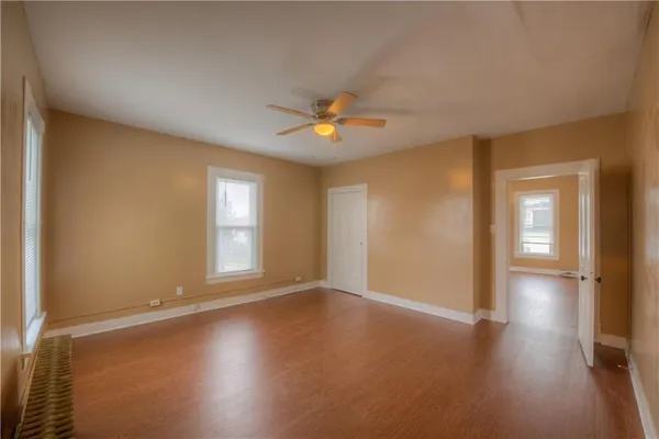 a view of an empty room with window and wooden floor