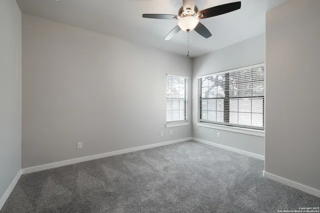 an empty room with windows and fan