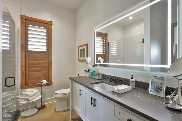 a bathroom with a granite countertop sink and a toilet