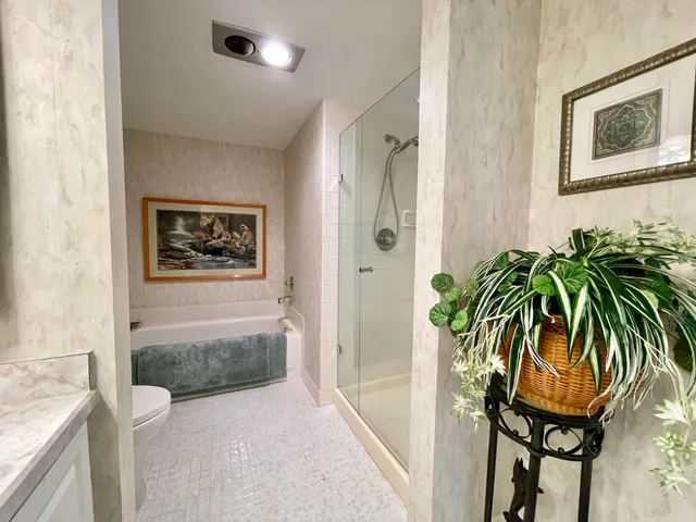 a hallway with painting on the wall and a potted plant