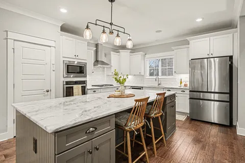 a kitchen with stainless steel appliances granite countertop a refrigerator a stove a sink dishwasher a oven with white cabinets and wooden floor