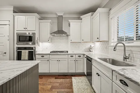 a kitchen with stainless steel appliances granite countertop a sink stove oven and white cabinets