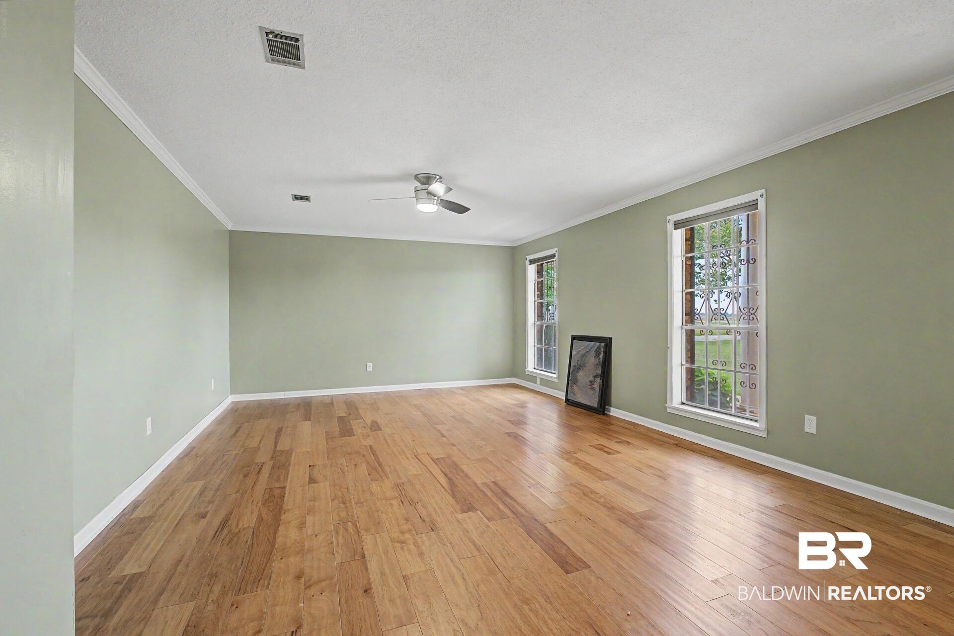 3791 Robinsonville Road Atmore, AL 36502 - Photo 33 of 47 Spacious room featuring wood-finish flooring, light green walls, and white crown molding