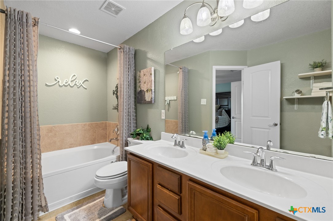 9142 Sage Loop Court Temple, TX 76502 - Photo 19 of 27 a bathroom with a sink a toilet a large mirror and shower