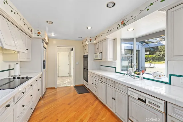 a large white kitchen with a large window and stainless steel appliances