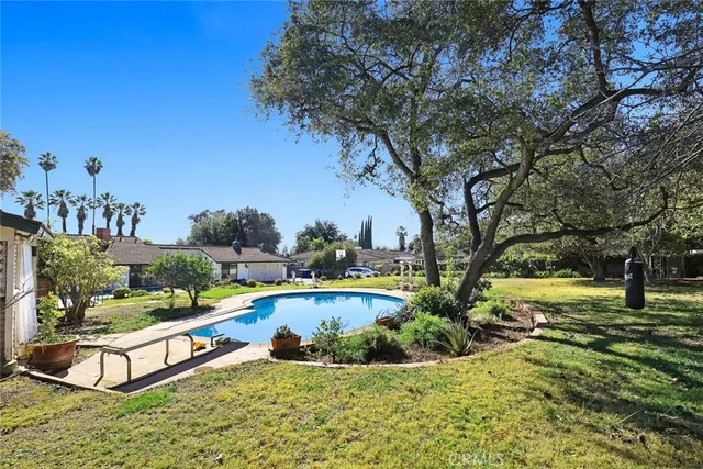 a view of a swimming pool with a patio and a yard