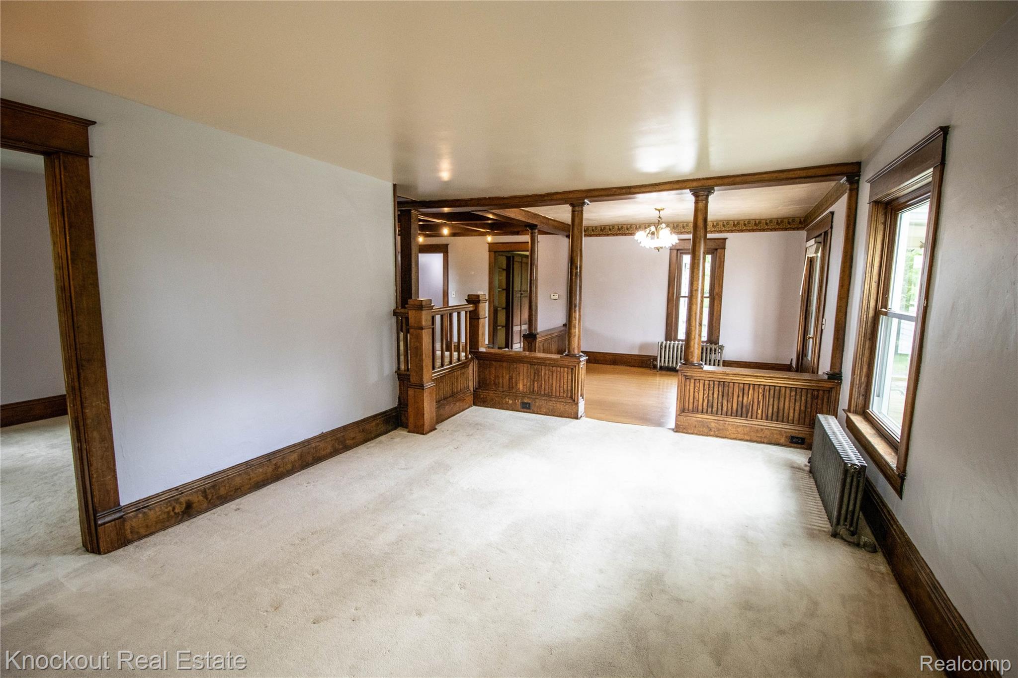 19983 West Ridge Road Henderson, MI 48841 - Photo 7 of 76 Carpeted interior space featuring extensive wood trim, wood-clad architectural columns, and baseboard radiators