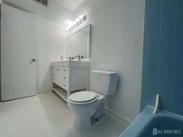 a bathroom with a granite countertop toilet and a sink
