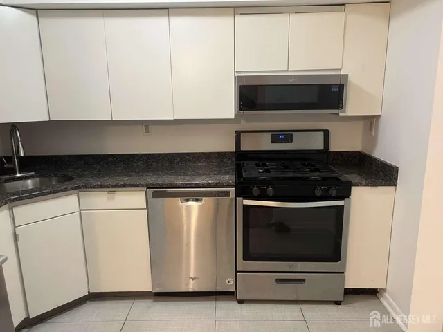 a kitchen with stainless steel appliances a stove a microwave and white cabinets