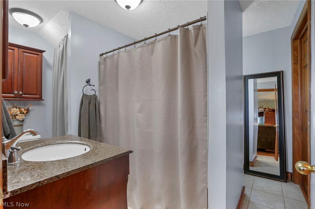 5502 Dutch Ridge Road New Straitsville, OH 43766 - Photo 28 of 49 Bathroom with vanity, a textured ceiling, a shower with curtain, and light tile patterned floors