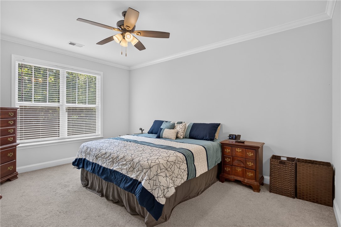 711 Barnes Road Seneca, SC 29672 - Photo 16 of 34 An inviting sleeping area features a ceiling fan, crown molding, and plush carpeting for ultimate comfort.
