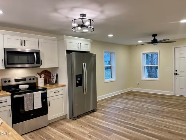 a kitchen with stainless steel appliances granite countertop a refrigerator a stove a sink dishwasher and a microwave oven on the wooden floor