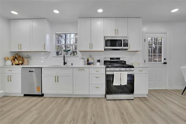 a kitchen with white cabinets stainless steel appliances and sink
