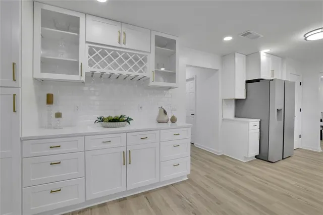 a kitchen with white cabinets stainless steel appliances and wooden floor