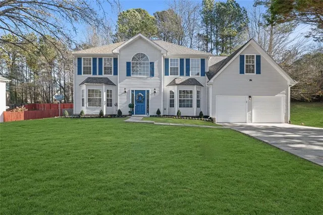 a front view of a house with a garden and trees