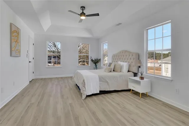 a spacious bedroom with a large bed a chandelier and windows