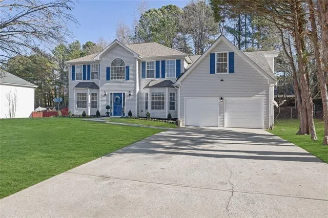 a front view of a house with a garden and trees