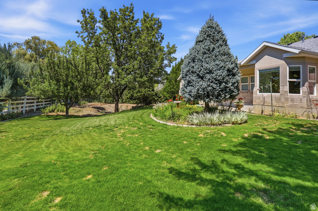 2190 750 West Perry, UT 84302 - Photo 5 of 42 Expansive backyard featuring a lush lawn, mature trees, and a white picket fence